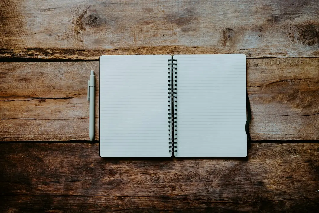 An open blank notebook and a pen on a wooden table, ready for a checklist to compare IPTV services like Glomax8K