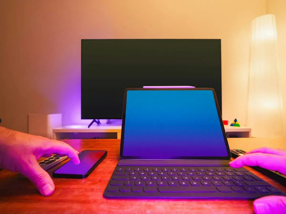 A tablet, a smartphone and a remote on a desk in front of a flat-screen TV, ready to test a Glomax8K free trial